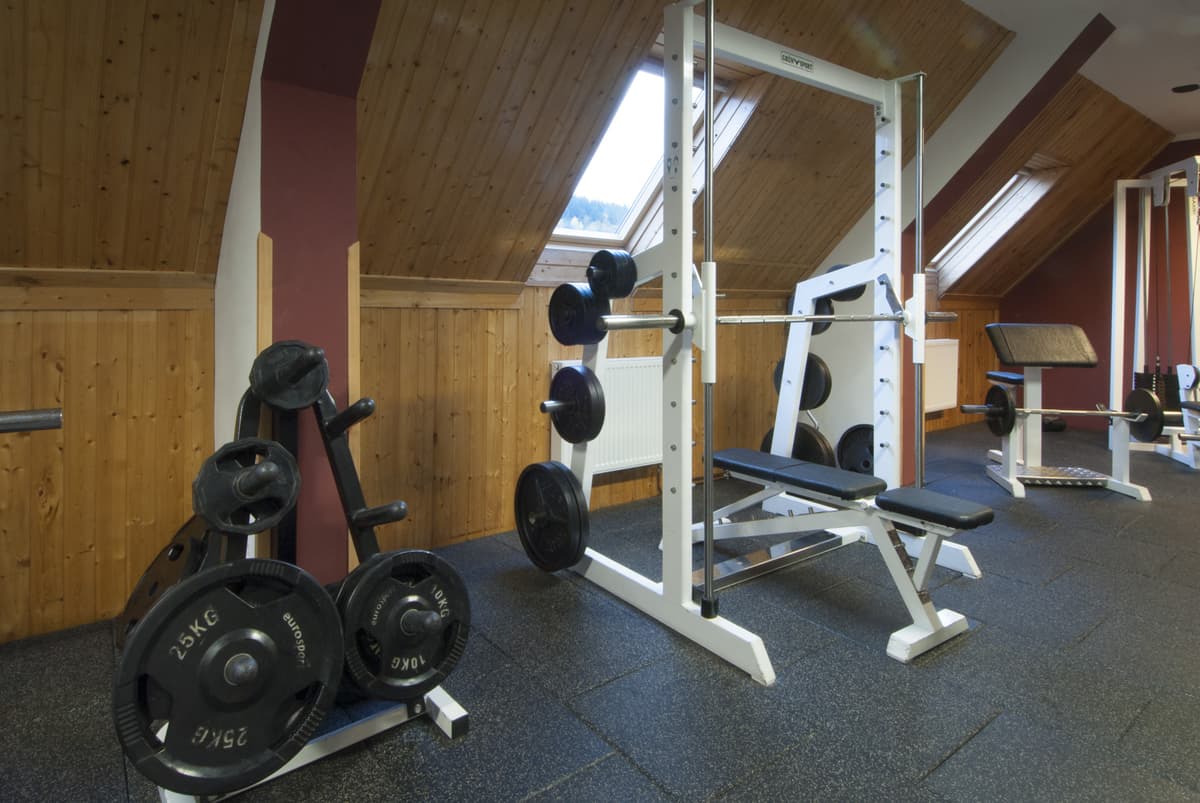 Fitnessraum mit einer Holzdecke, einer Ziegelwand und Trainingsgeräten.