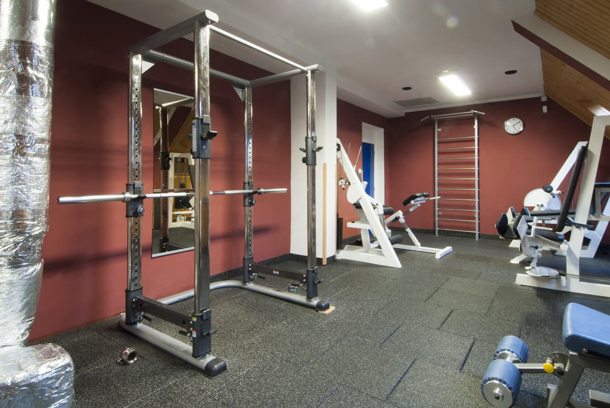 Fitnessraum mit mehreren Geräten und Holzvertäfelung im Innenraum.