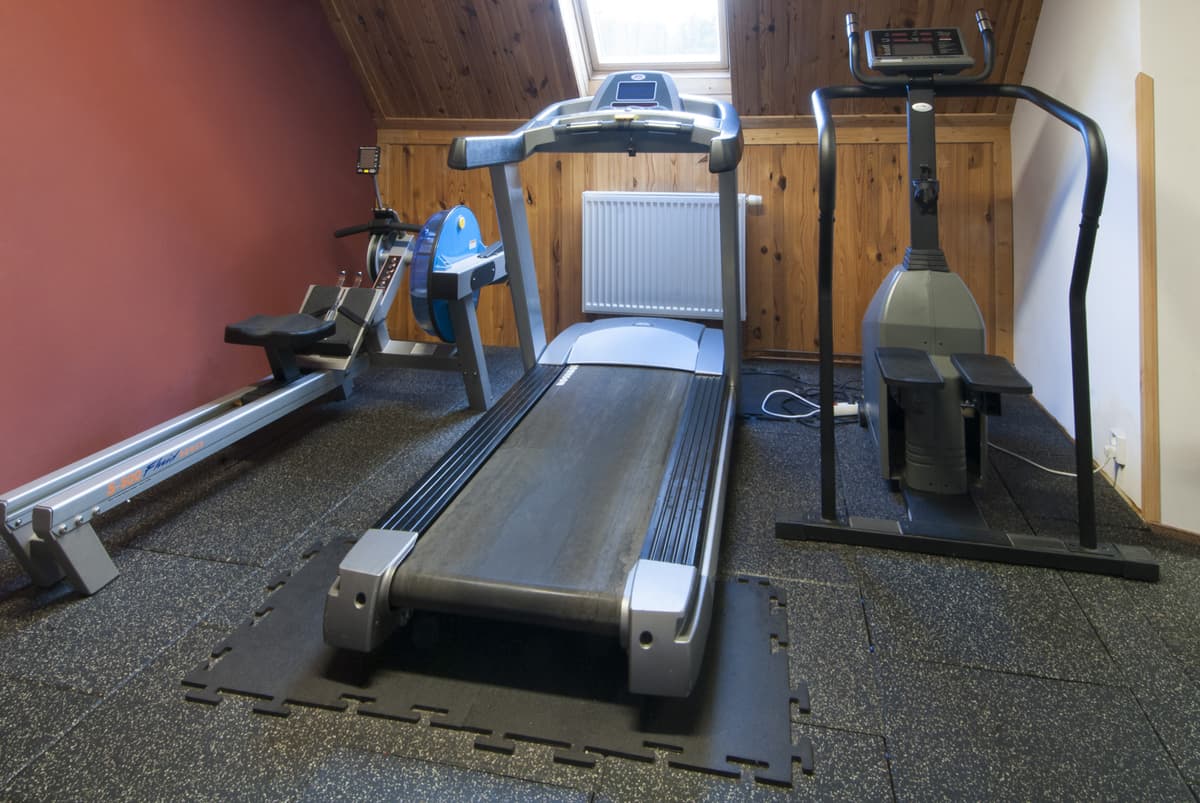 Ein Laufband in einem Fitnessraum mit roten Wänden und Holzvertäfelung.