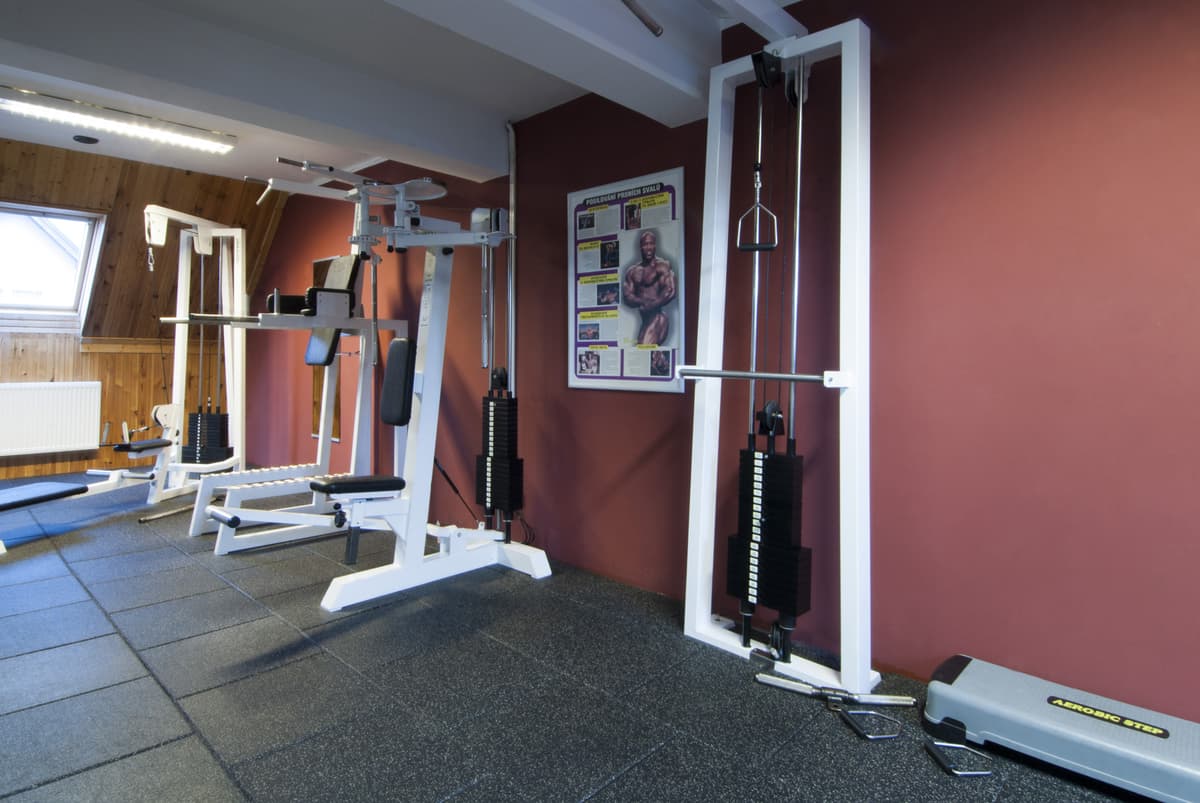 Fitnessraum mit einem Spiegel und einer Trainingsbank, Bilder hängen an der Wand.