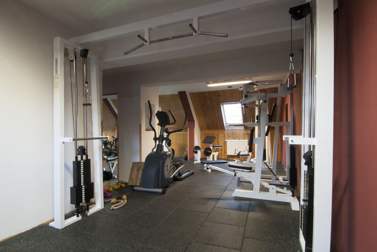 Ein Überblick über den Fitnessraum mit mehreren Geräten und einer Hantelbank.