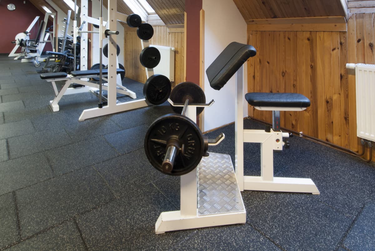 Teil des Fitnessraums mit einer Hantelbank und Hanteln auf dem Boden.