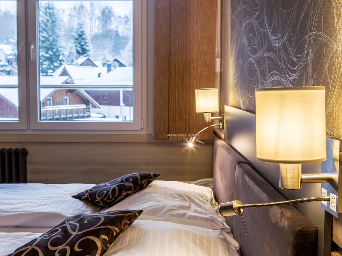 View of bed and lamp by the window in a double room