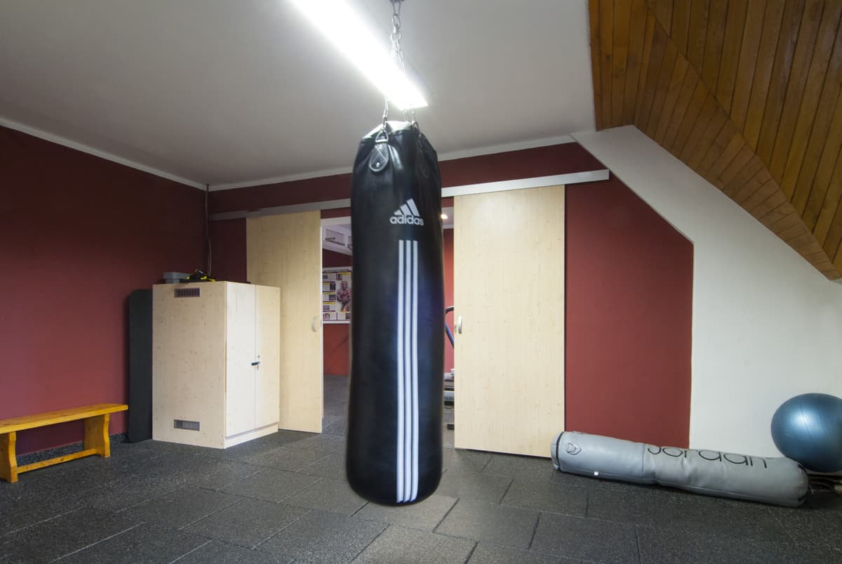 A punching bag hanging in the corner of the gym for fitness and boxing training.