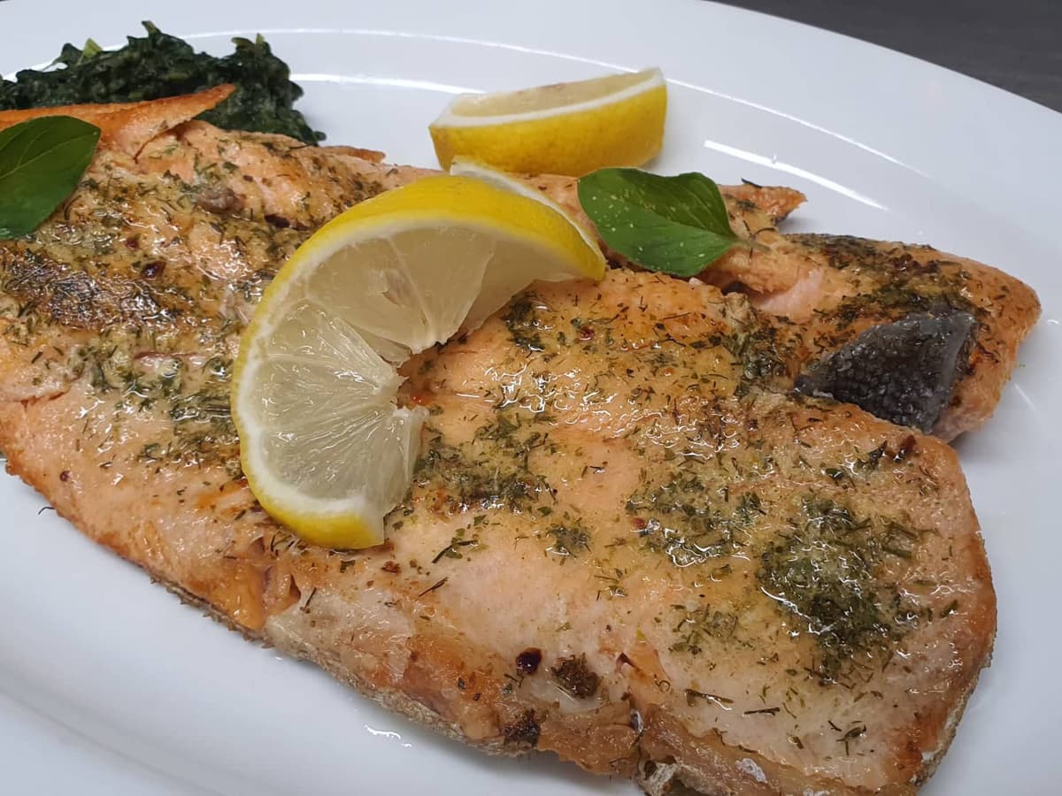 Plate with baked salmon fillet, herbs and lemon.