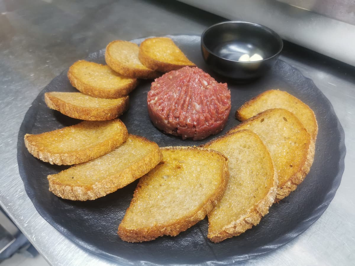Beef tartare on a slate board with toast.