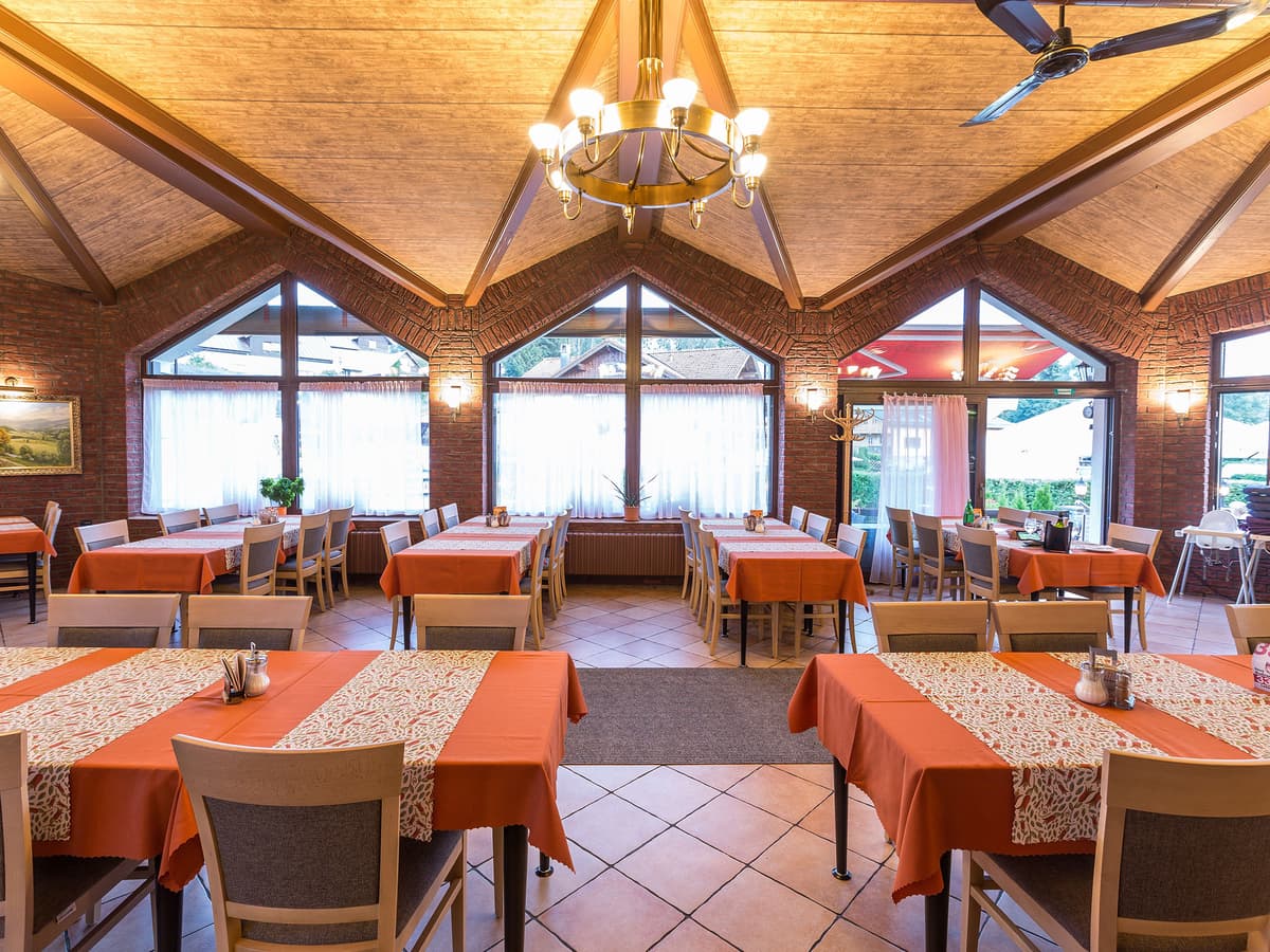 Dining area with large windows, wood paneling and brick details.