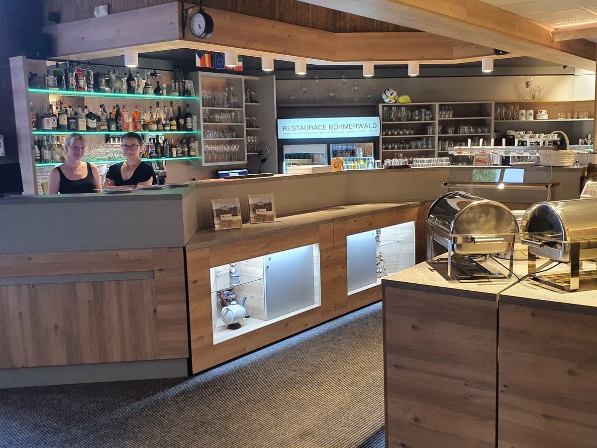 Part of the restaurant with a modern counter and a display case with dishes. Bar is in the background.
